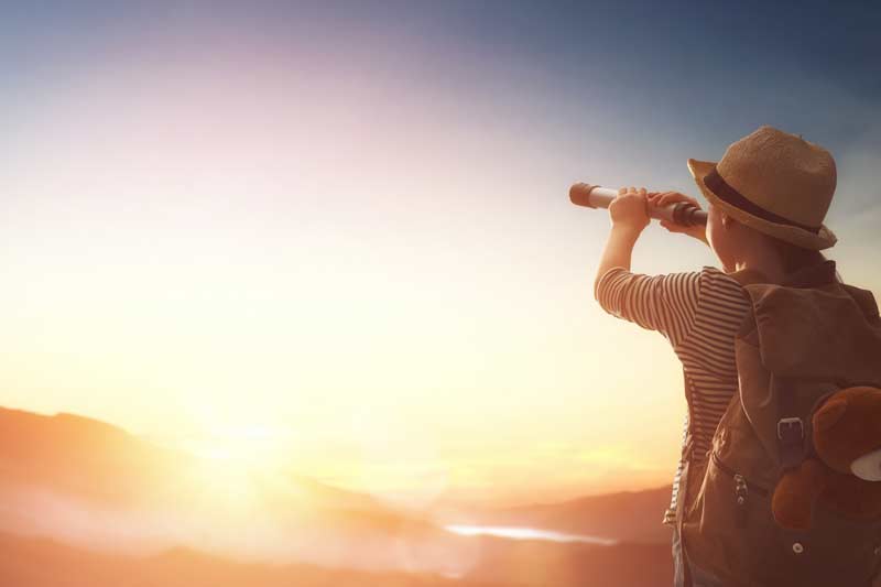 Kind blickt mit Fernrohr Richtung Horizont